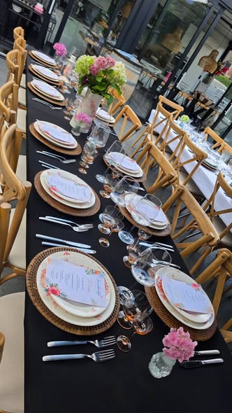Gestylede tafel met zwart kleed, rieten placemats en roze pioenrozen