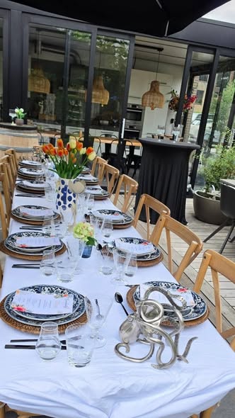 Buitentafel met wit linnen, blauw-wit servies en oranje tulpen